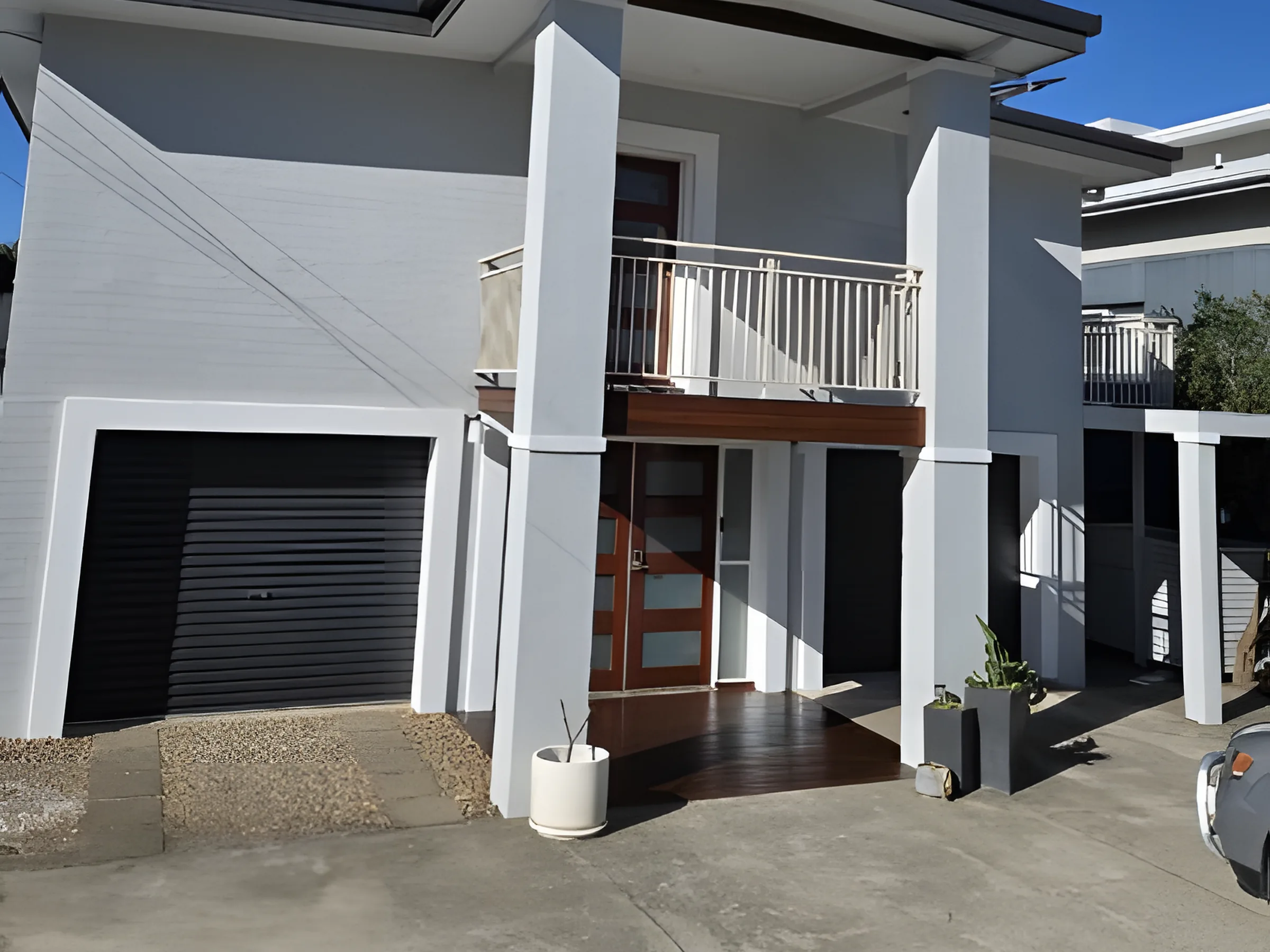 A two storey rendered townhouse painted white with charcoal doors
