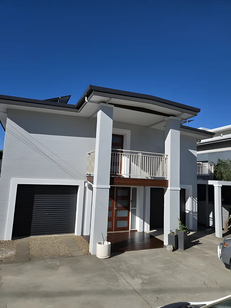 A two storey white rendered townhouse with a timber balcony
