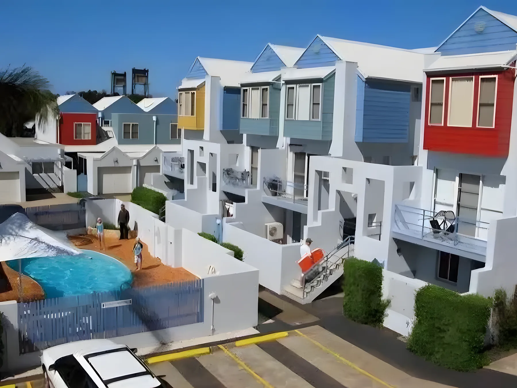 A row of coastal townhouses painted white with coloured feature panels